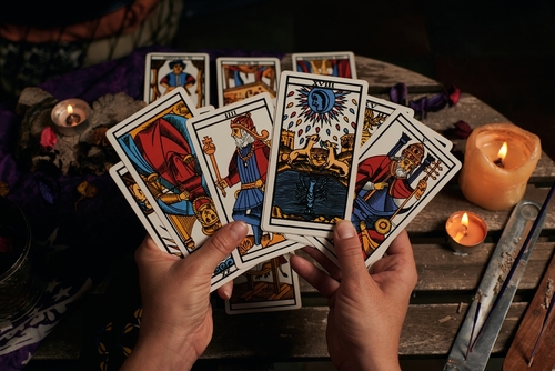 Two hands holding a selection of tarot cards